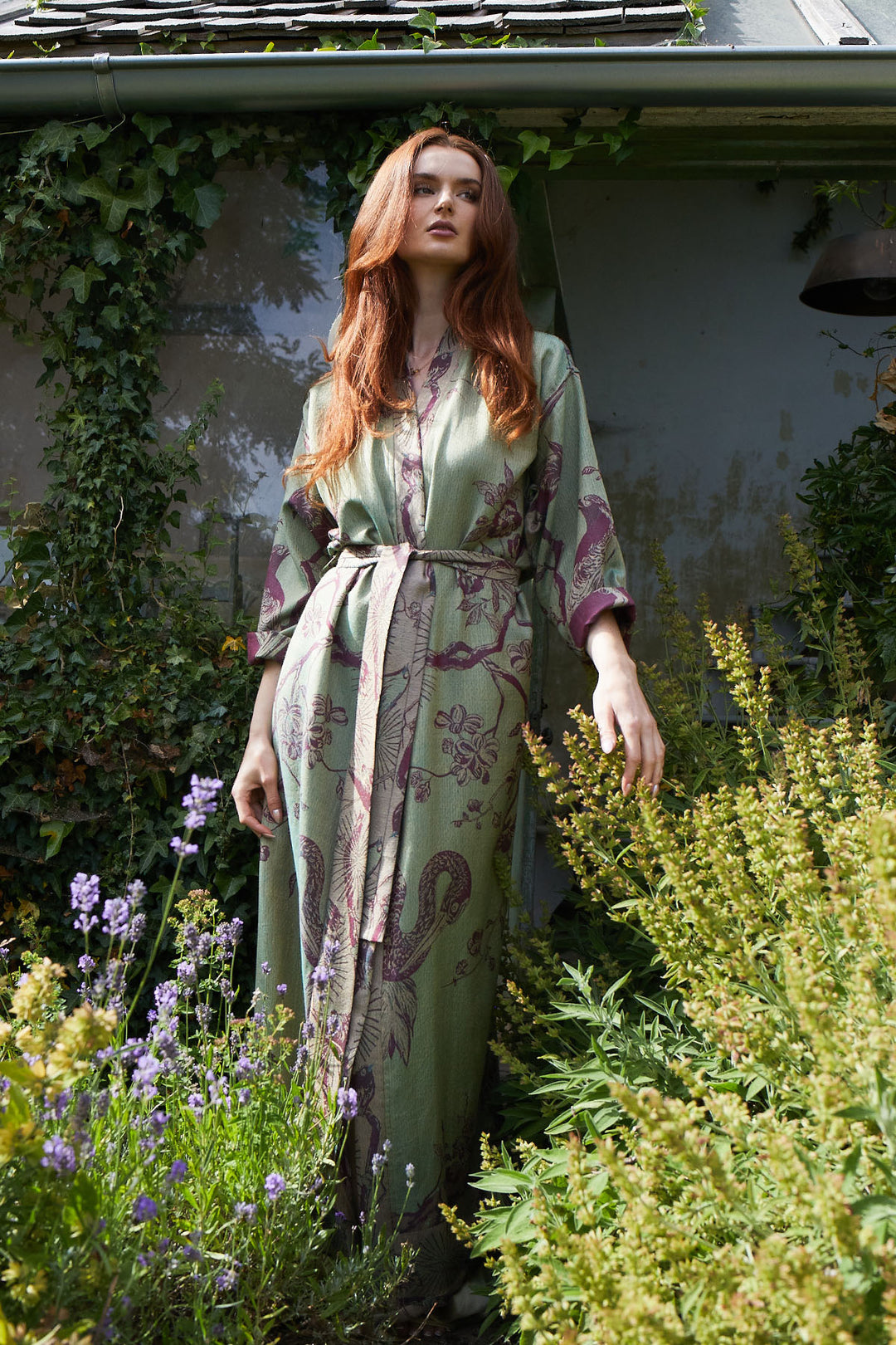 Woman in a floral dressing gown standing among plants and flowers