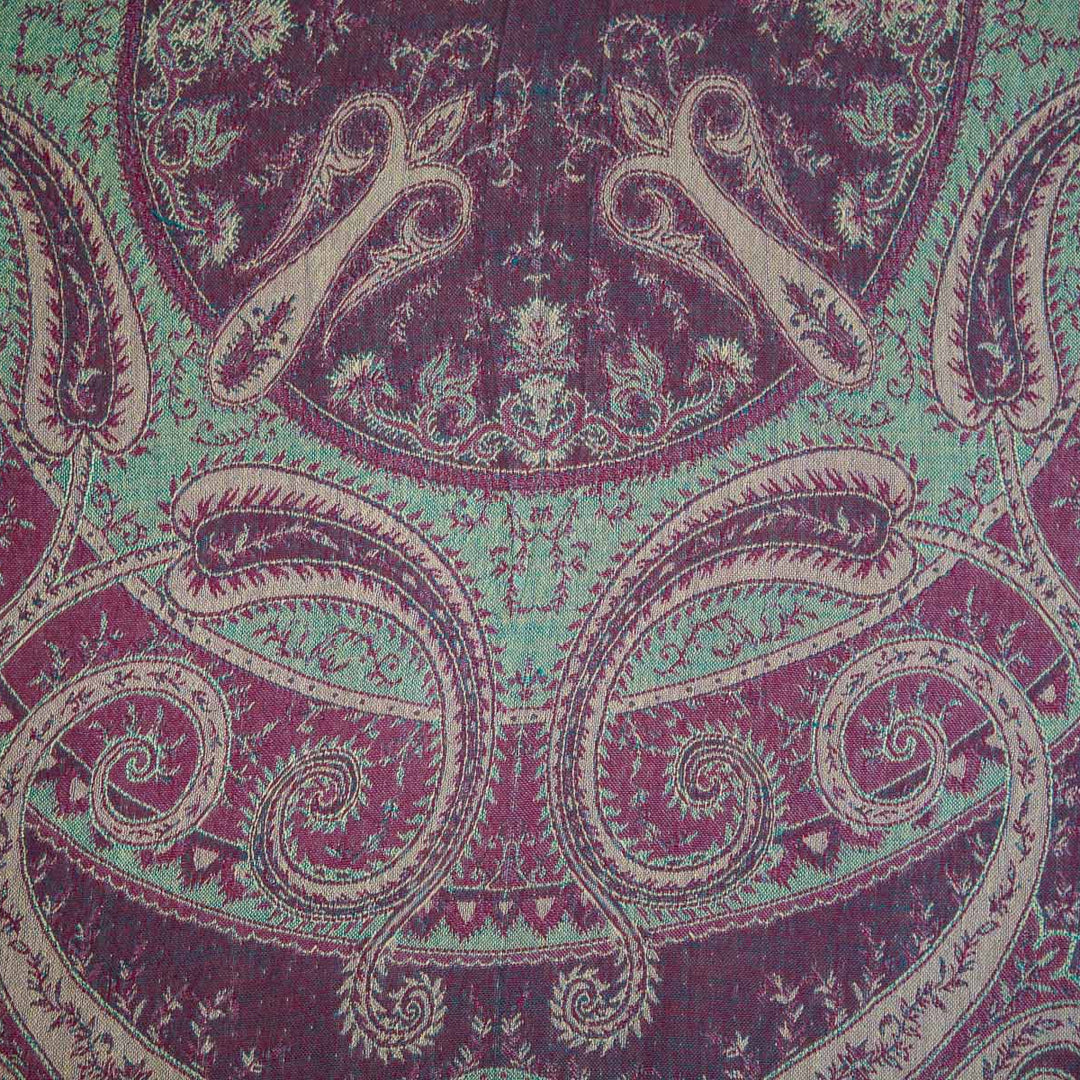 Close-up of a fabric with intricate paisley pattern in purple and green.