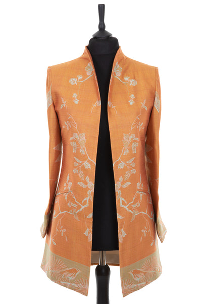Womens longline jacket with a soft curved collar in an apricot orange cashmere fabric with a pale green pattern