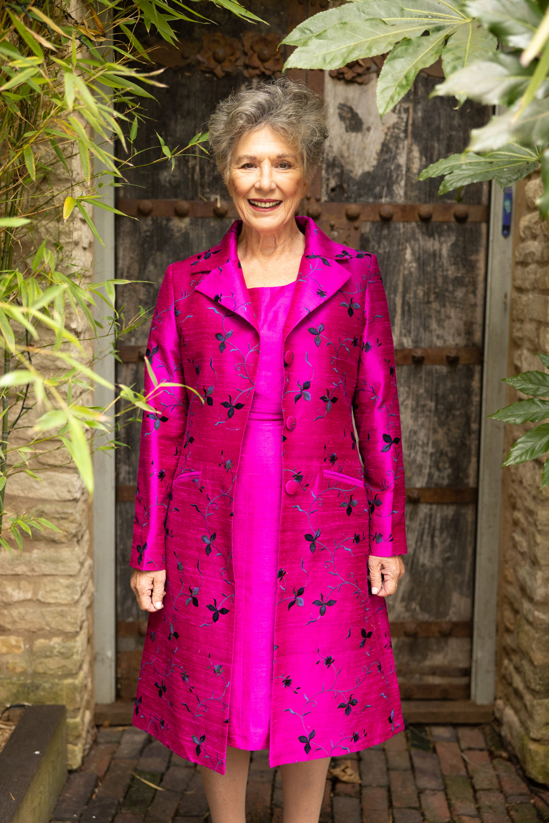 Elegant pink mid length coat for ladies. Bright silk fabric coat with black and blue flowers. Mother of the bride pink coat and pink dress.