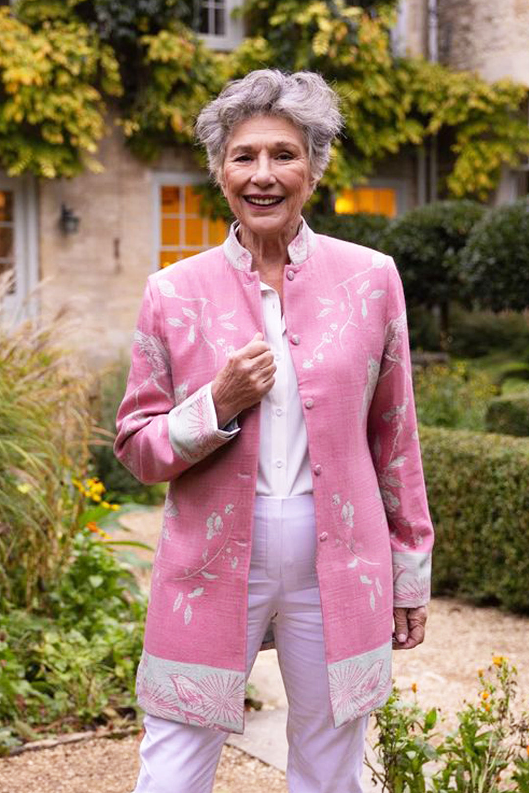 Pink longline jacket with white flowers. Older lady in elegant outfit.