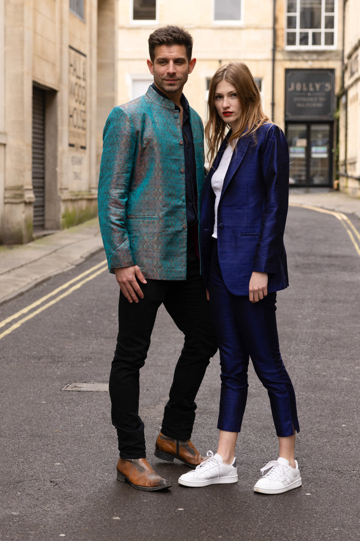 women in navy silk suit worn with trainers and man wearing silk nehru jacket