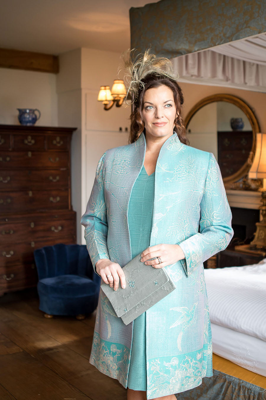 Mother of the bride or groom wearing a cashmere coat with matching silk dress. Light blue wedding outfit.