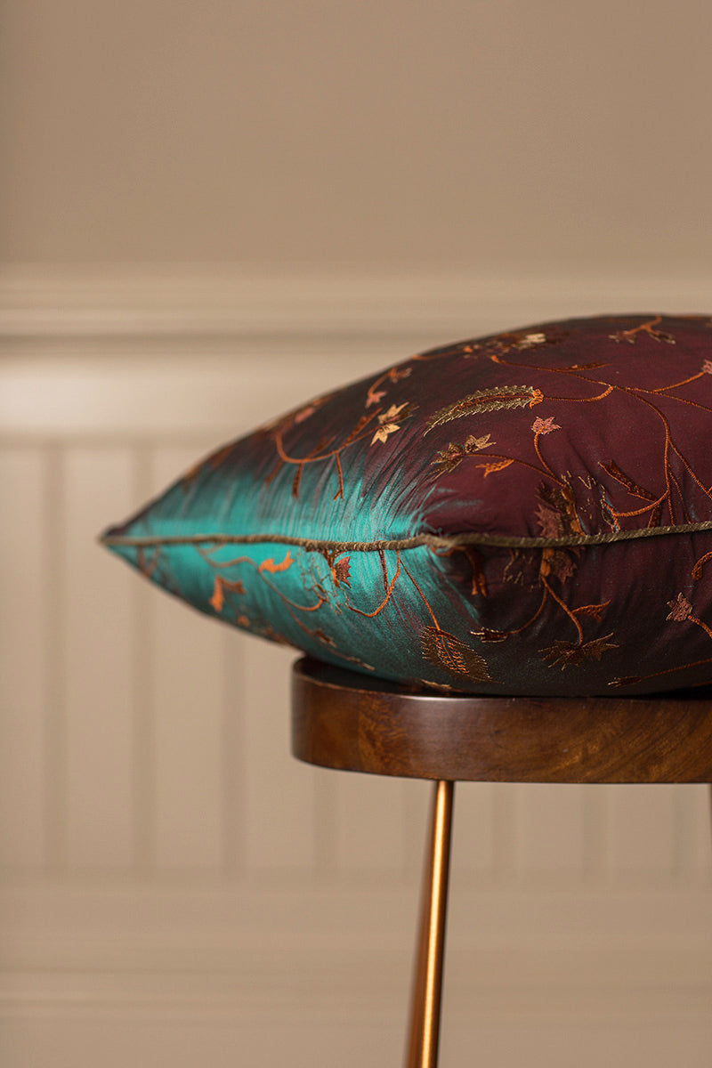 Green bed cushion with embroidered flowers.