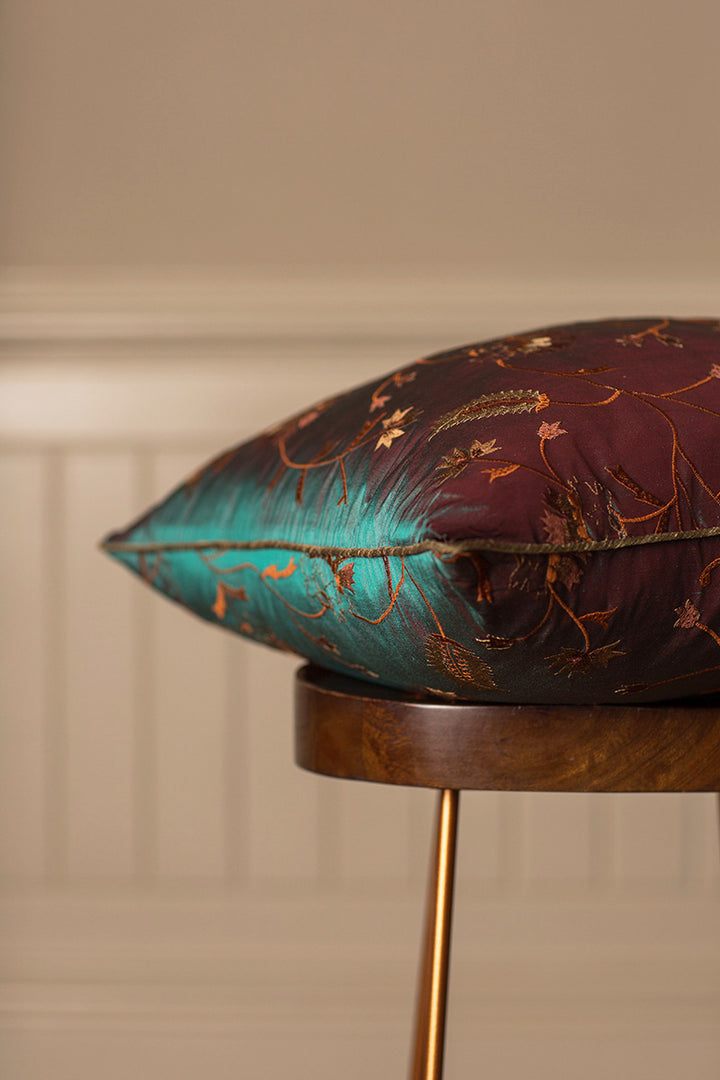 Green bed cushion with embroidered flowers.