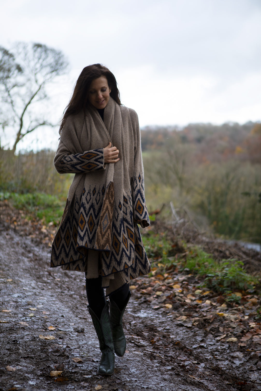 Lady walking on a path, wearing wool cardigan and matching scarf in natural colours.