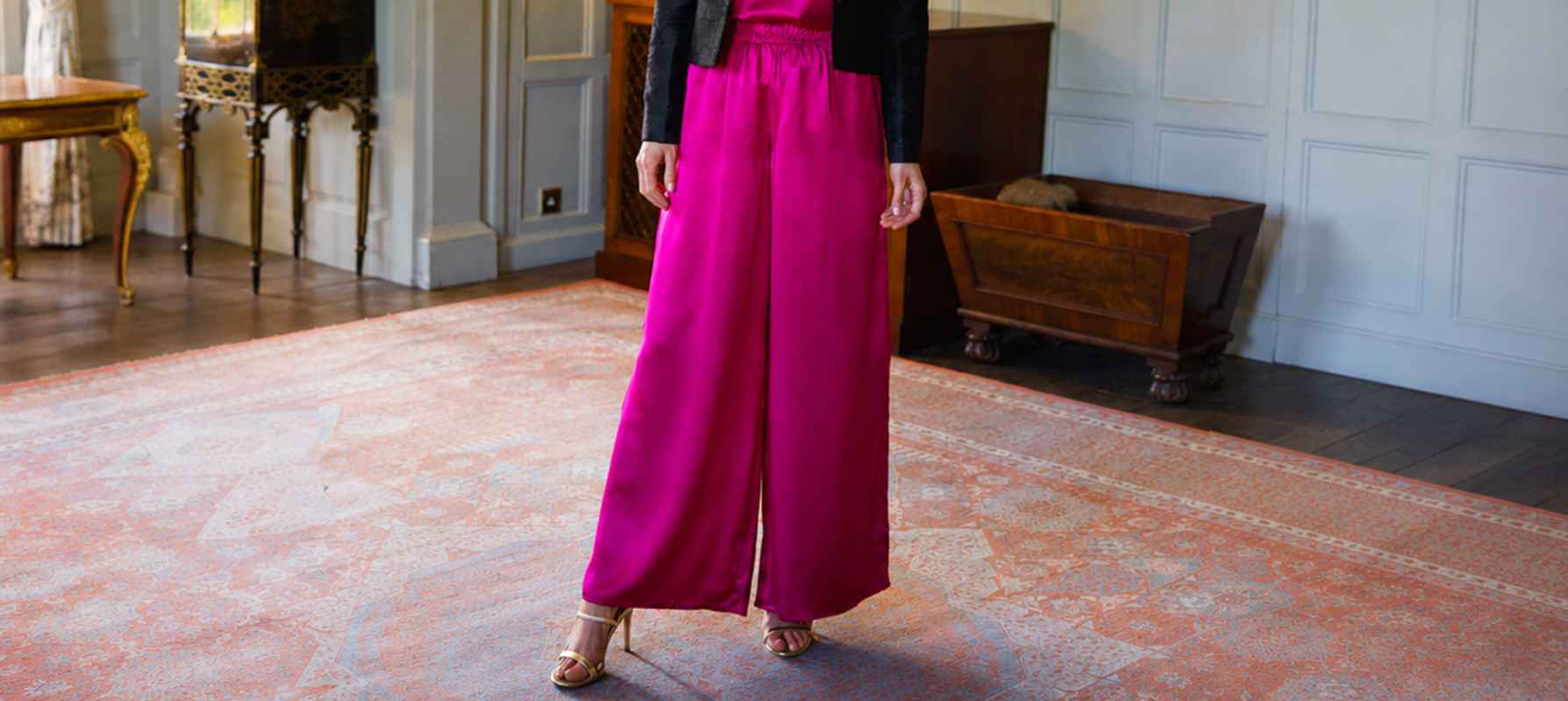 Woman wearing bright pink silk palazzo pants with a wide-leg silhouette and elasticated waistband, styled for elegant occasionwear and special events.
