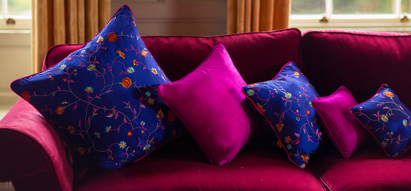 selection of silk cusions on a sofa, blue patterned silk cushion and pink plain silk cushion