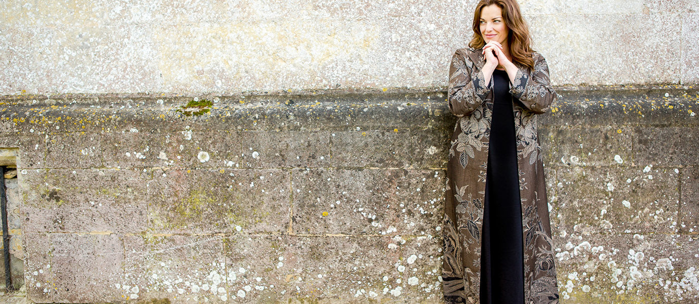 A dark haired woman in a plus size cashmere coat, ideal outfit for plus size mother of the bride or wedding guest. 