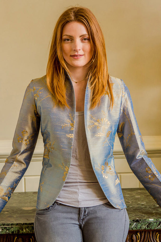 Smart short jacket in silver worn by young woman with blond hair. 