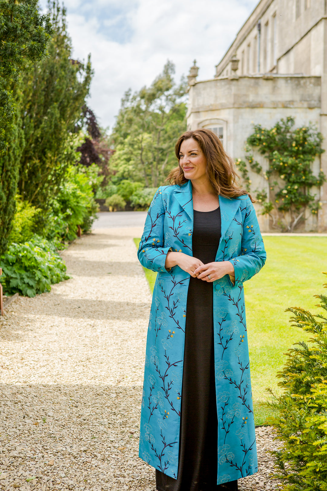Women wearing the Shibumi Aquila coat in turquoise outside of a stately home
