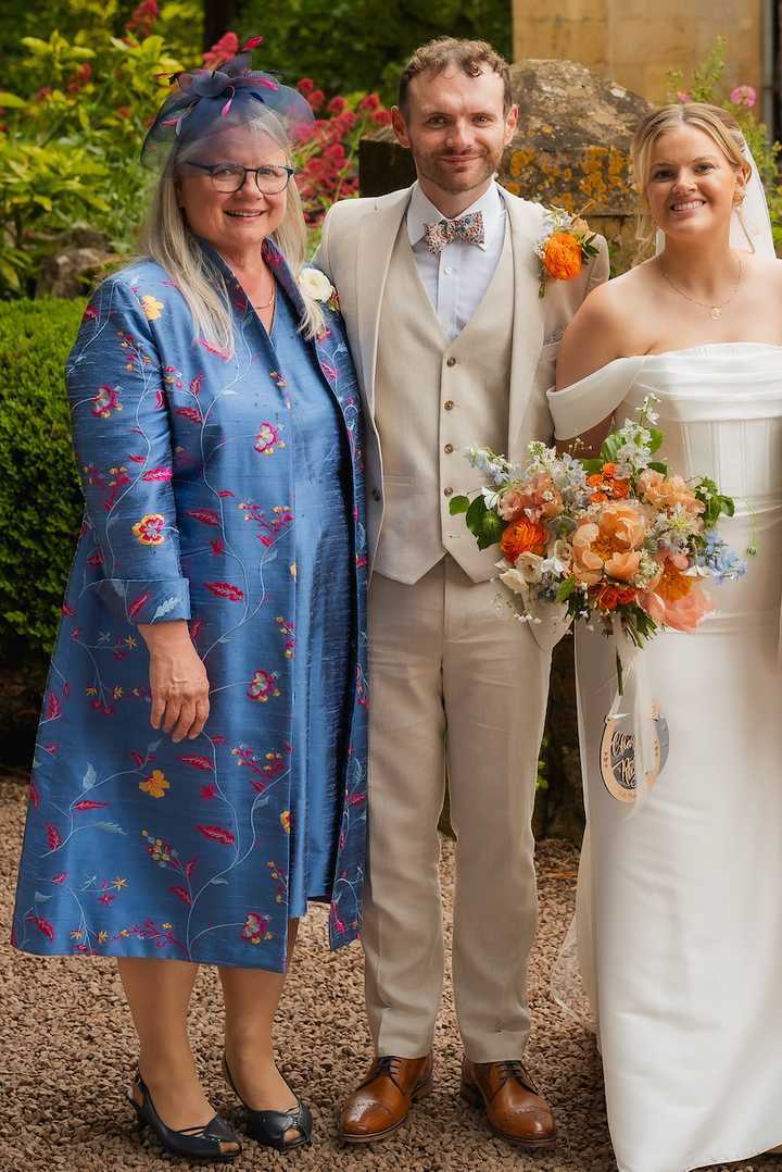 Wedding party standing in front of a historic building with floral arrangements.