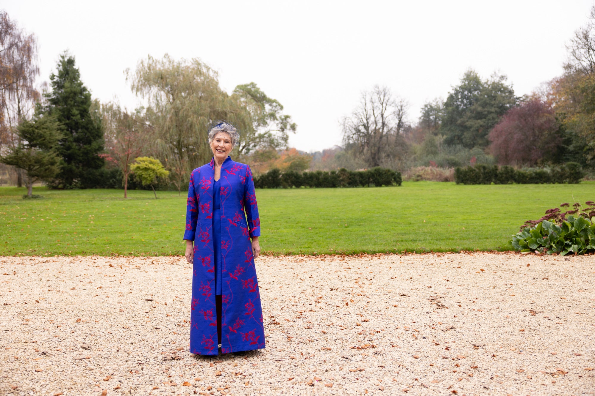 Mother of the groom outfit. Full length blue coat with flowers. Blue silk maxi coat with big red floral pattern. Worn with matching silk dress in blue. 