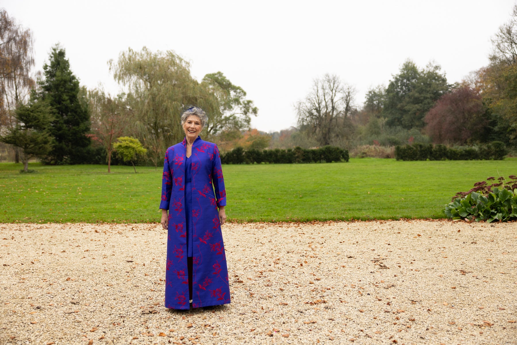 Mother of the bride wearing full length silk coat in blue with red floral pattern. Matching blue dress. 