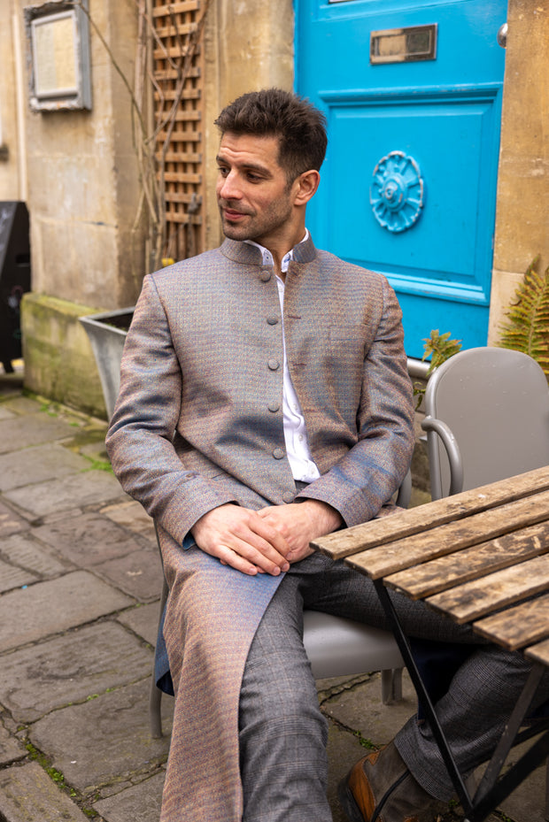 man sitting at the cafe wearing smart coat in silver blue colour