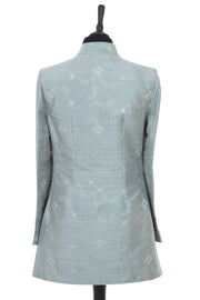 Womens longline jacket with a half belt, in a pale grey blue embroidered raw silk with a subtle pattern in very pale grey and turquoise