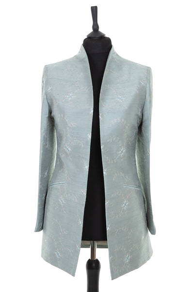 Womens longline jacket with a soft curved collar in a pale grey blue embroidered raw silk with a subtle pattern in very pale grey and turquoise