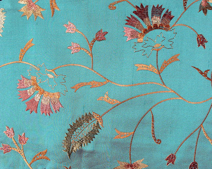 teal coloured silk fabric with golden and red embroidery. Fabric sample