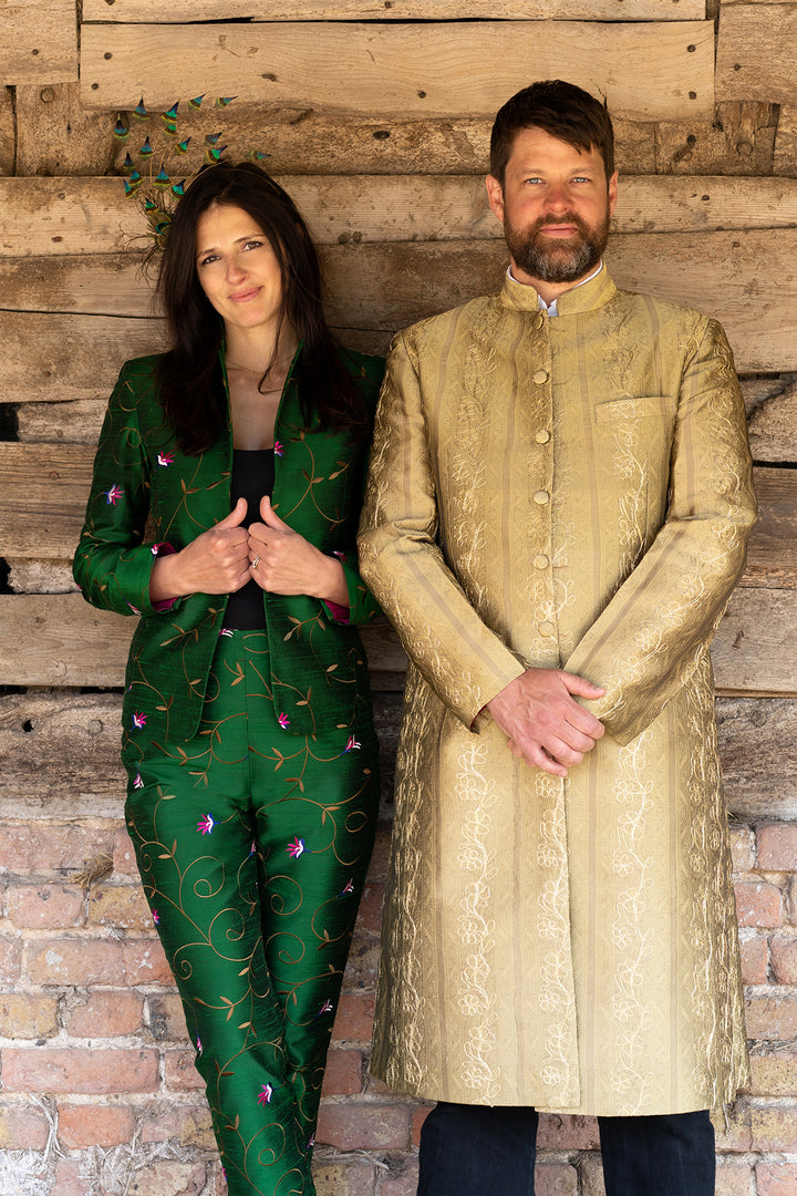 Wedding guests. Women is wearing green Shibumi suit and the men is wearing knee length gold jacket with hight collar. 