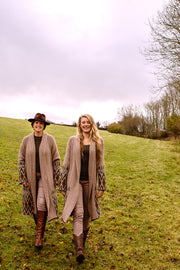 Two women walking side by side dressed in longline wool cardigans. 